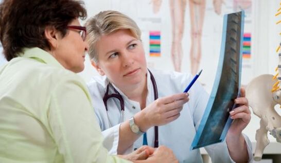 un médico examina una radiografía para detectar dolor de espalda